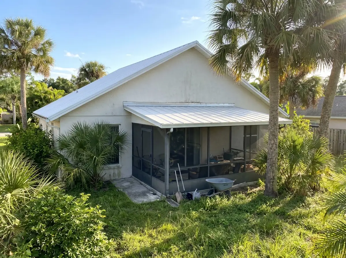 Low-pitch porch roof in metal panels tied into the main roof of a single-story CBS house